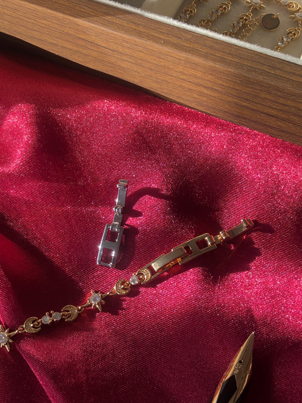 Gold bracelet with star-shaped charms on a red fabric background