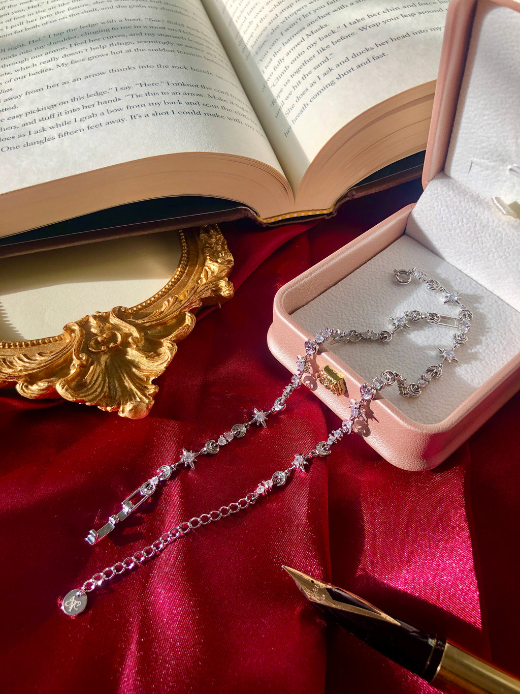 Sterling Silver Celestial themed bracelets on a red fabric with an open book and gold frame in the background