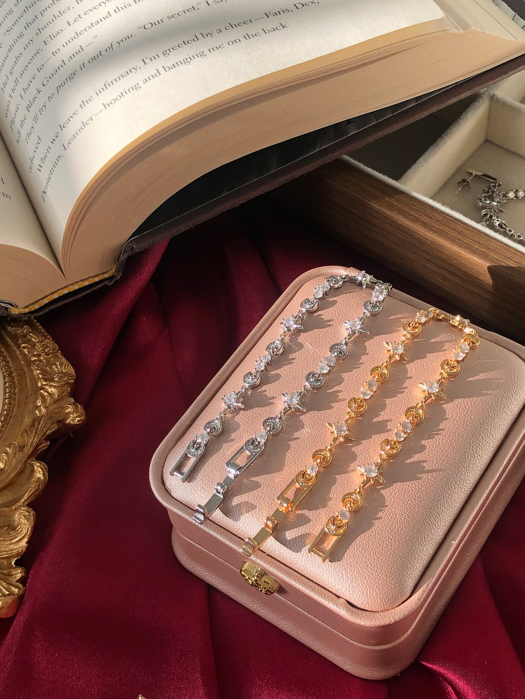 Pink jewelry box with a silver and 18K gold romatasy inspired tennis bracelet on a red fabric background