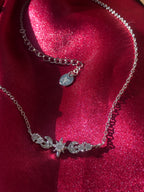 Silver necklace with star and moon charms on a red fabric background