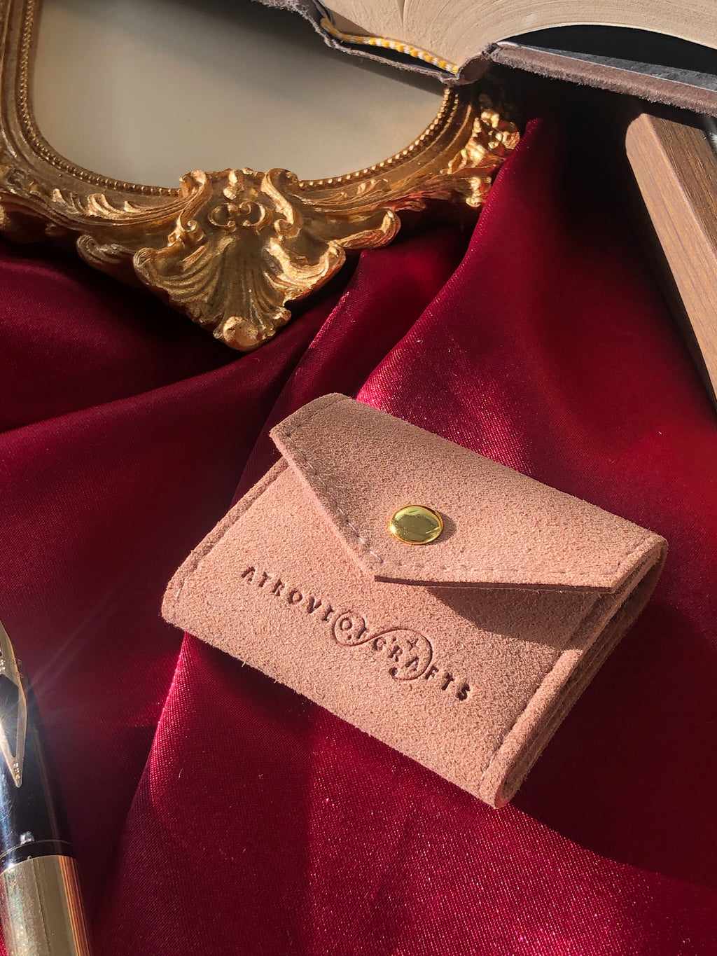 Travel sized light pink pouch on a red satin background
