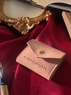 Travel sized light pink pouch on a red satin background